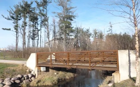 Steel-truss pedestrian bridge crossing over a campus pathway