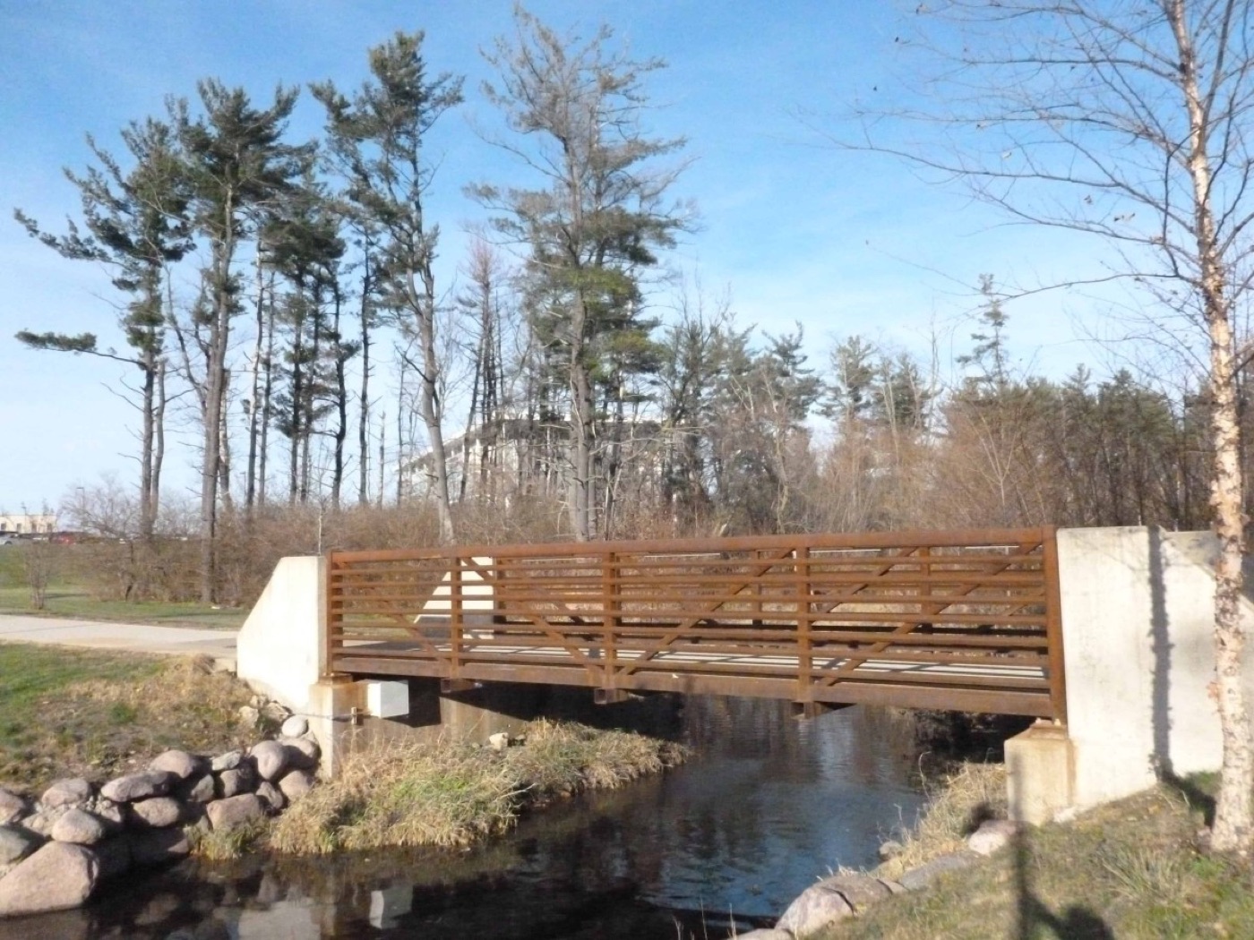 Steel-truss pedestrian bridge over a campus pathway